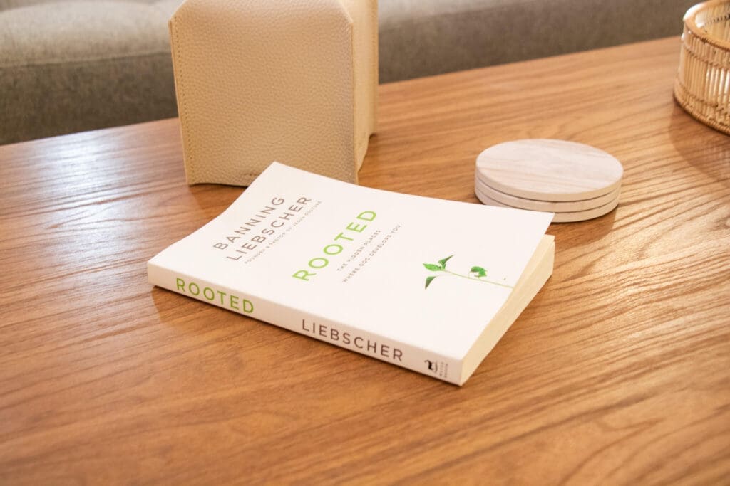 A book titled "Rooted" sits on a wooden table beside coasters and a tissue box. How does EMDR help you feel rooted again after trauma? A Christian therapist in Gilbert, AZ often draws on faith-based resources like this to support healing.