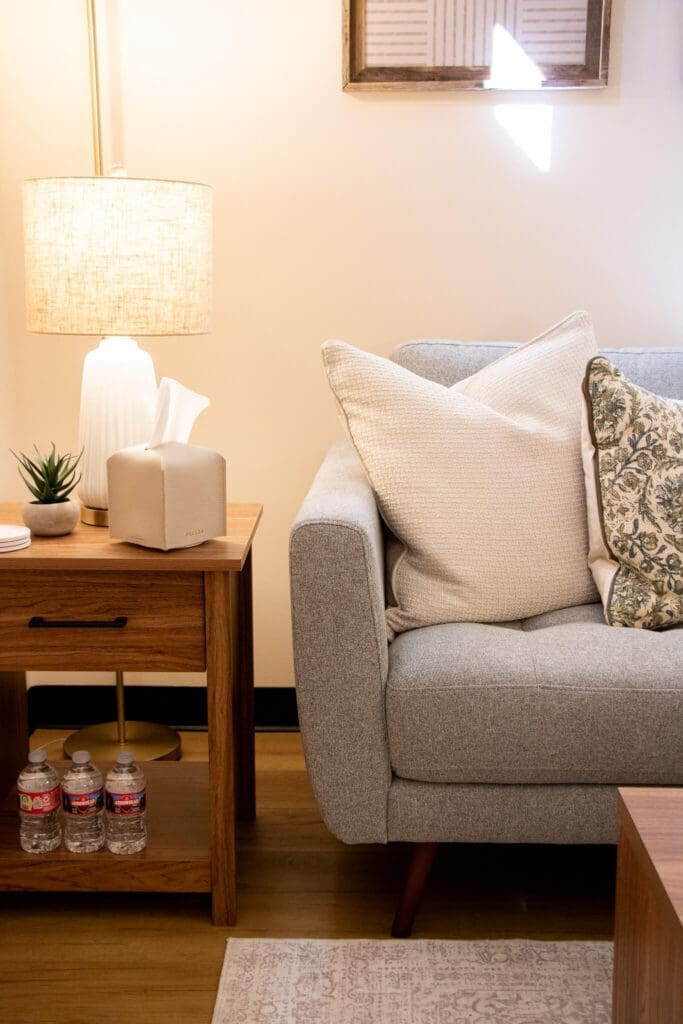 A calming therapy room features soft pillows, a warm lamp, and water bottles nearby. How can EMDR help release trauma stored in the body? Christian counseling in Gilbert, AZ offers a peaceful space to begin that healing process.